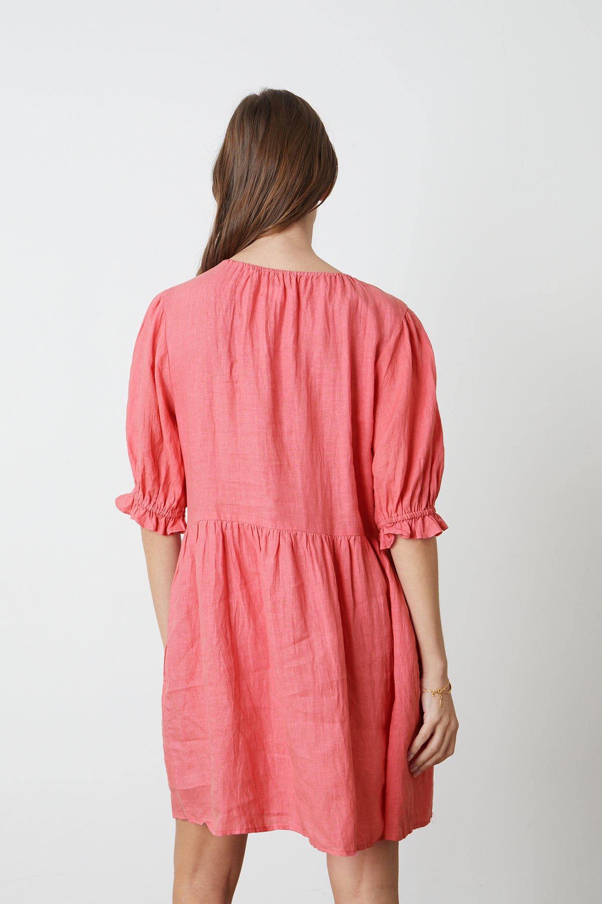 The back view of a woman wearing a Velvet by Graham & Spencer KAILANI LINEN PUFF SLEEVE DRESS.-26342704349377