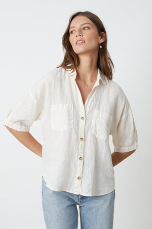 a model wearing a white MARIA LINEN BUTTON-UP SHIRT by Velvet by Graham & Spencer and jeans.