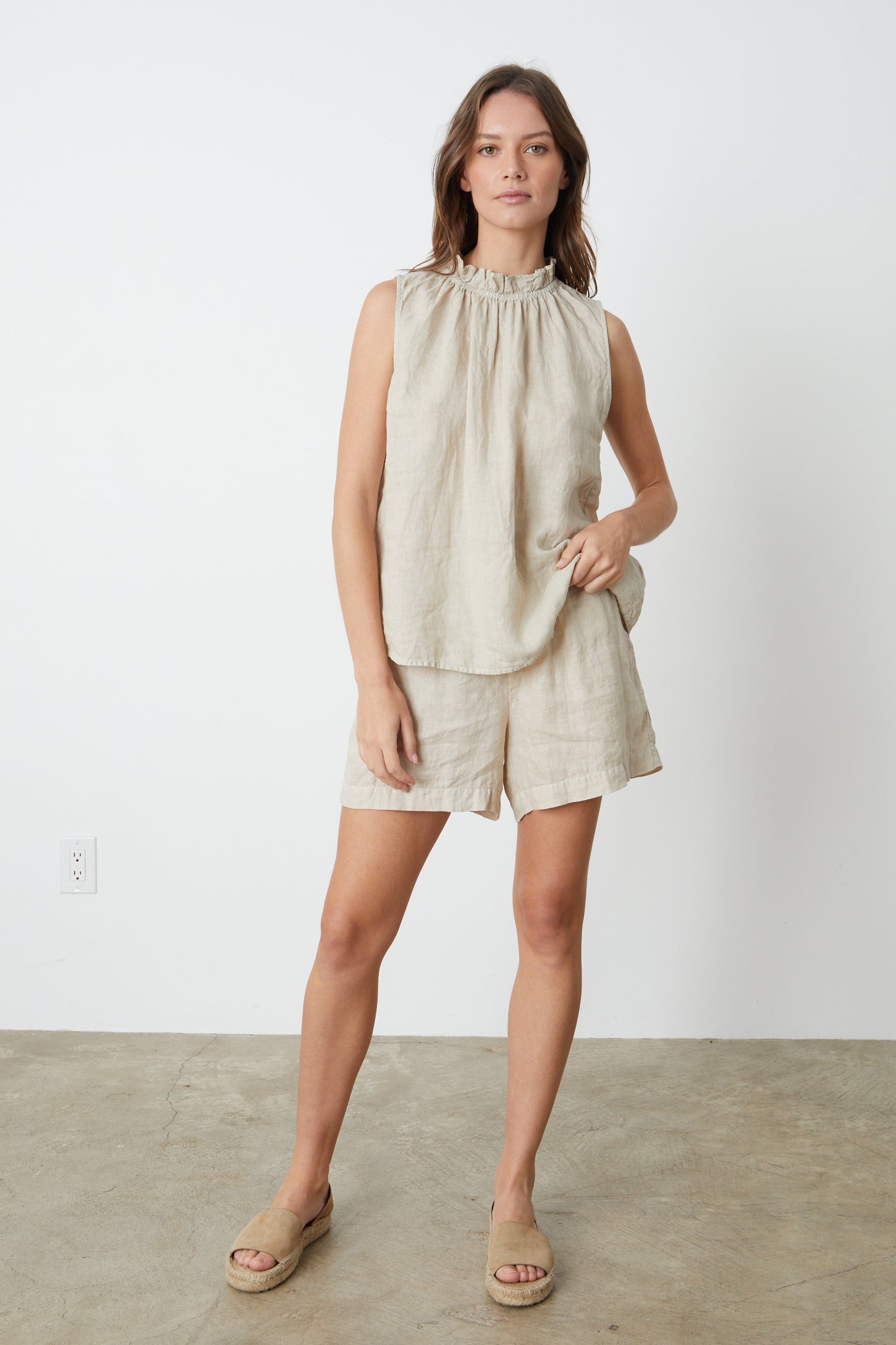 A woman wearing a sleeveless NOVA LINEN TOP by Velvet by Graham & Spencer and shorts in sand full length front shot with sandals.-26577321525441