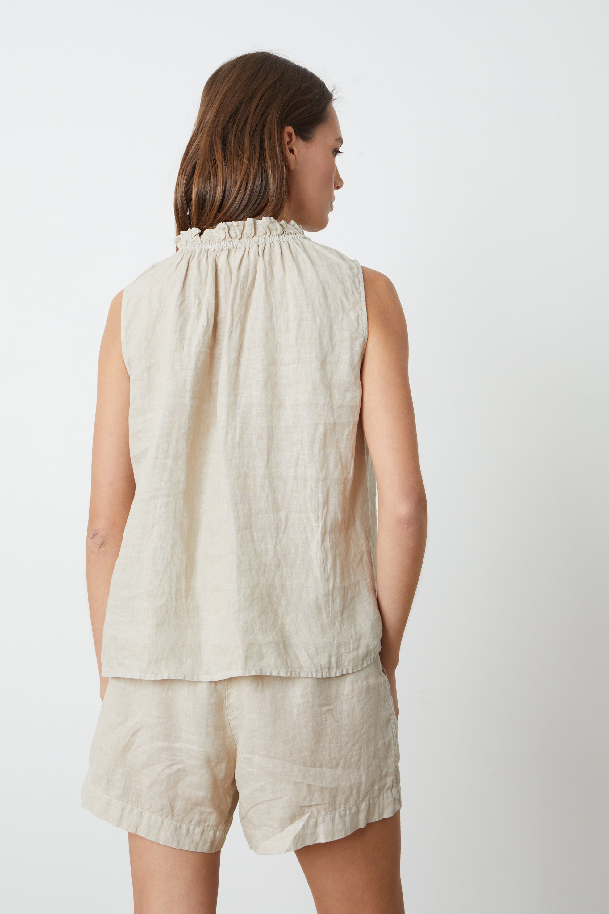   The back view of a woman wearing a Velvet by Graham & Spencer NOVA LINEN TOP and shorts. 