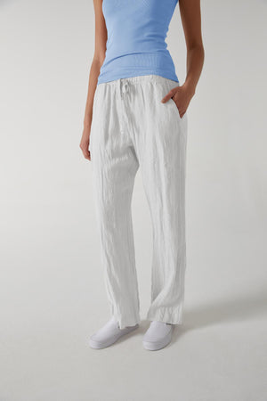 A woman wearing white linen PICO pants by Velvet by Jenny Graham and a relaxed fit blue top.