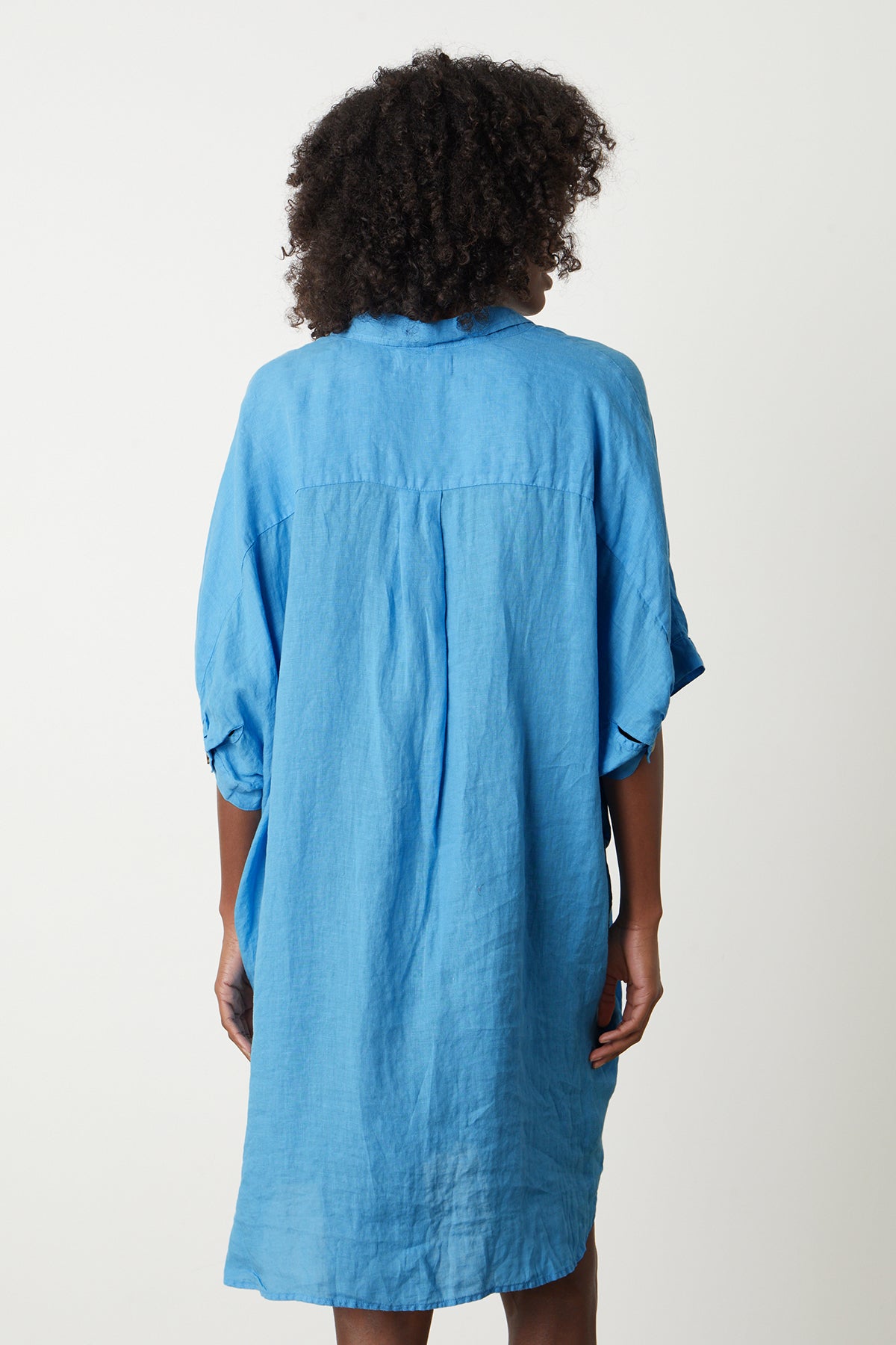 The back view of a woman wearing a blue STEVIE LINEN BUTTON-UP DRESS dress by Velvet by Graham & Spencer.-26342723616961
