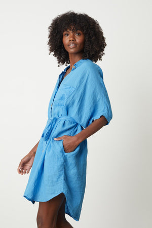 the model is wearing a blue Velvet by Graham & Spencer linen shirt dress.
