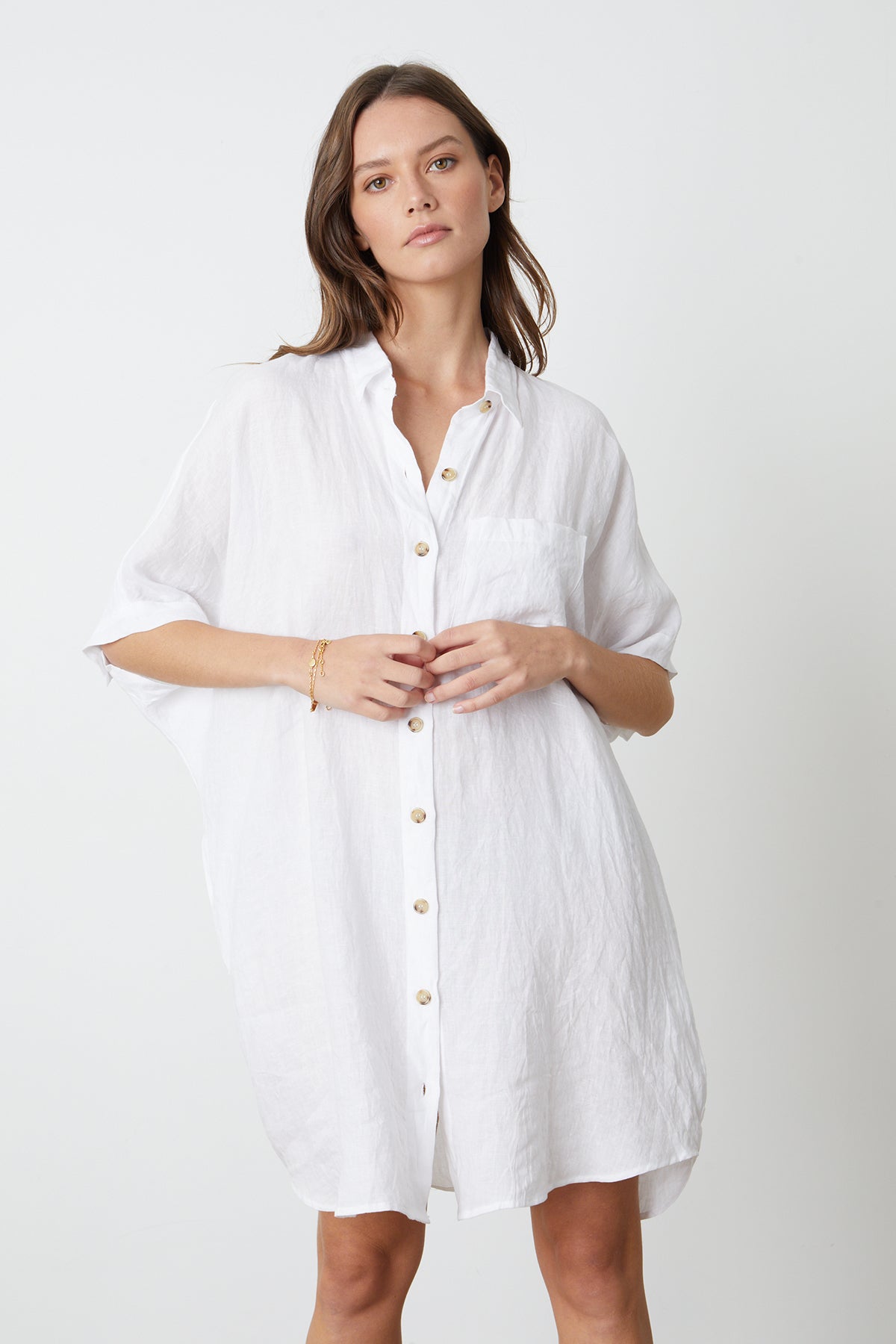   A model wearing a white STEVIE LINEN BUTTON-UP DRESS by Velvet by Graham & Spencer. 