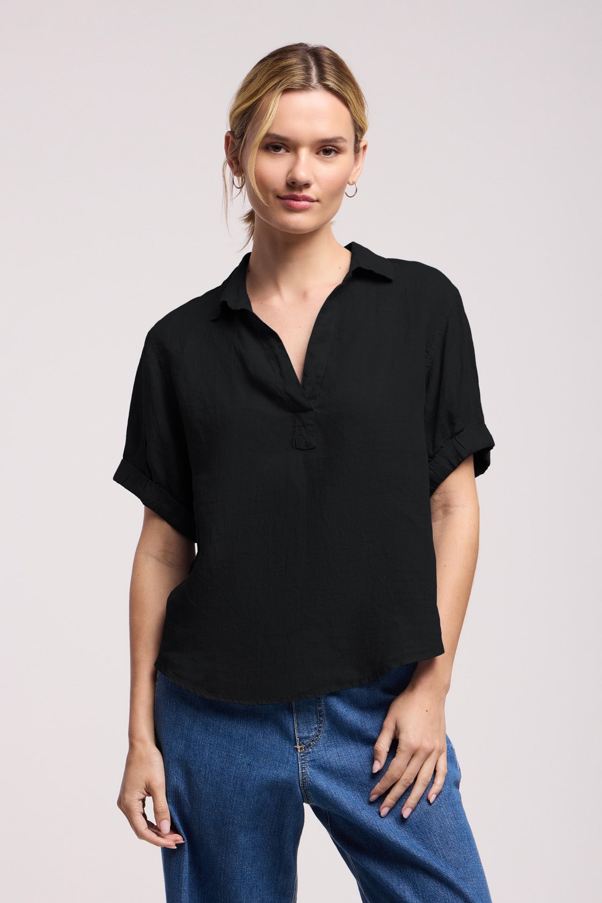 Dressed in Velvet by Graham & Spencer’s VIVICA LINEN TOP—a short-sleeve black collared shirt—paired with blue jeans, this look stands out against a plain light background as the ideal warm-weather ensemble. The lightweight linen and subtle split neckline bring effortless comfort and relaxed style to any summer day.
