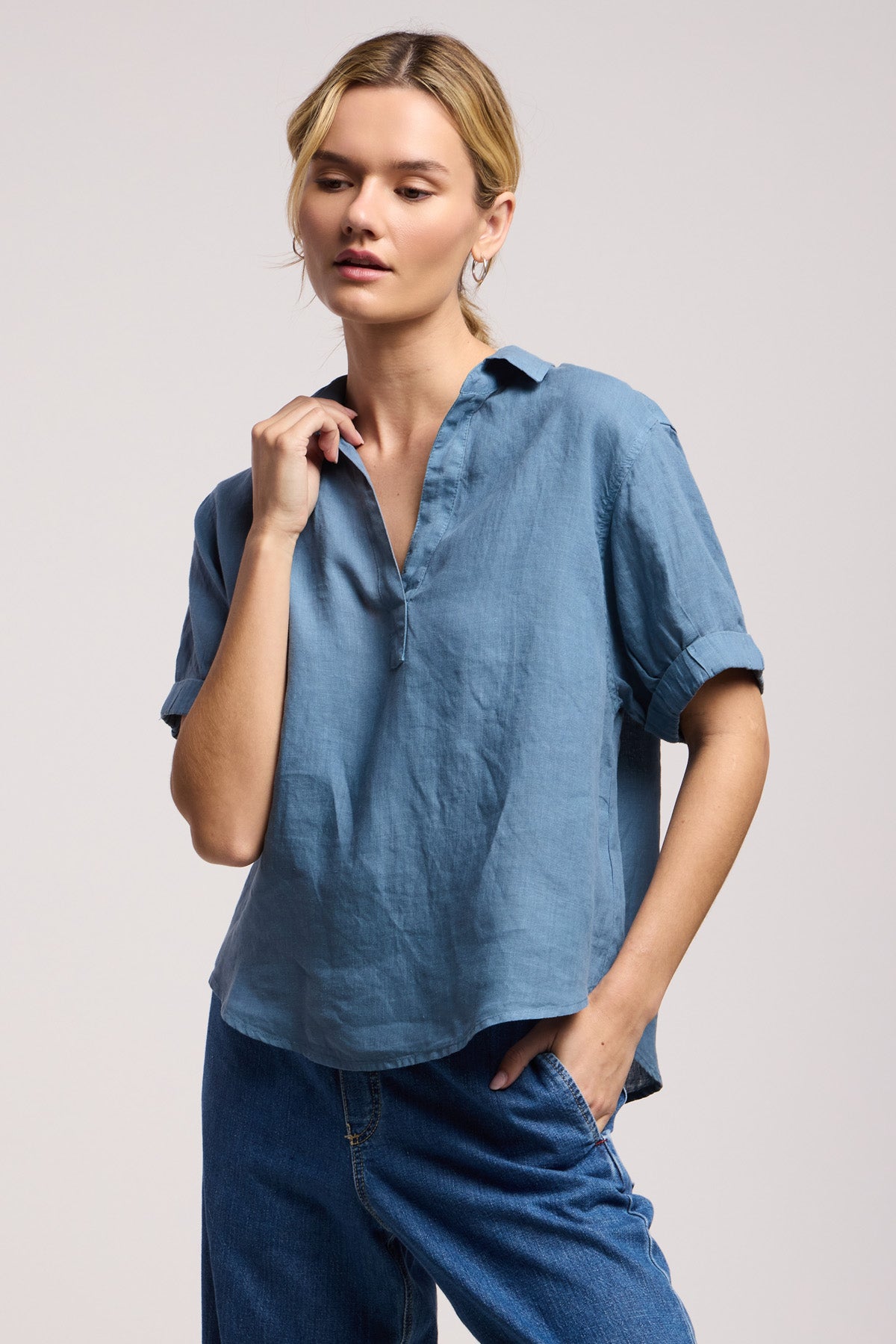 A person wearing the VIVICA LINEN TOP by Velvet by Graham & Spencer, styled with blue jeans against a simple backdrop—a breezy, lightweight option for effortless warm-weather style.