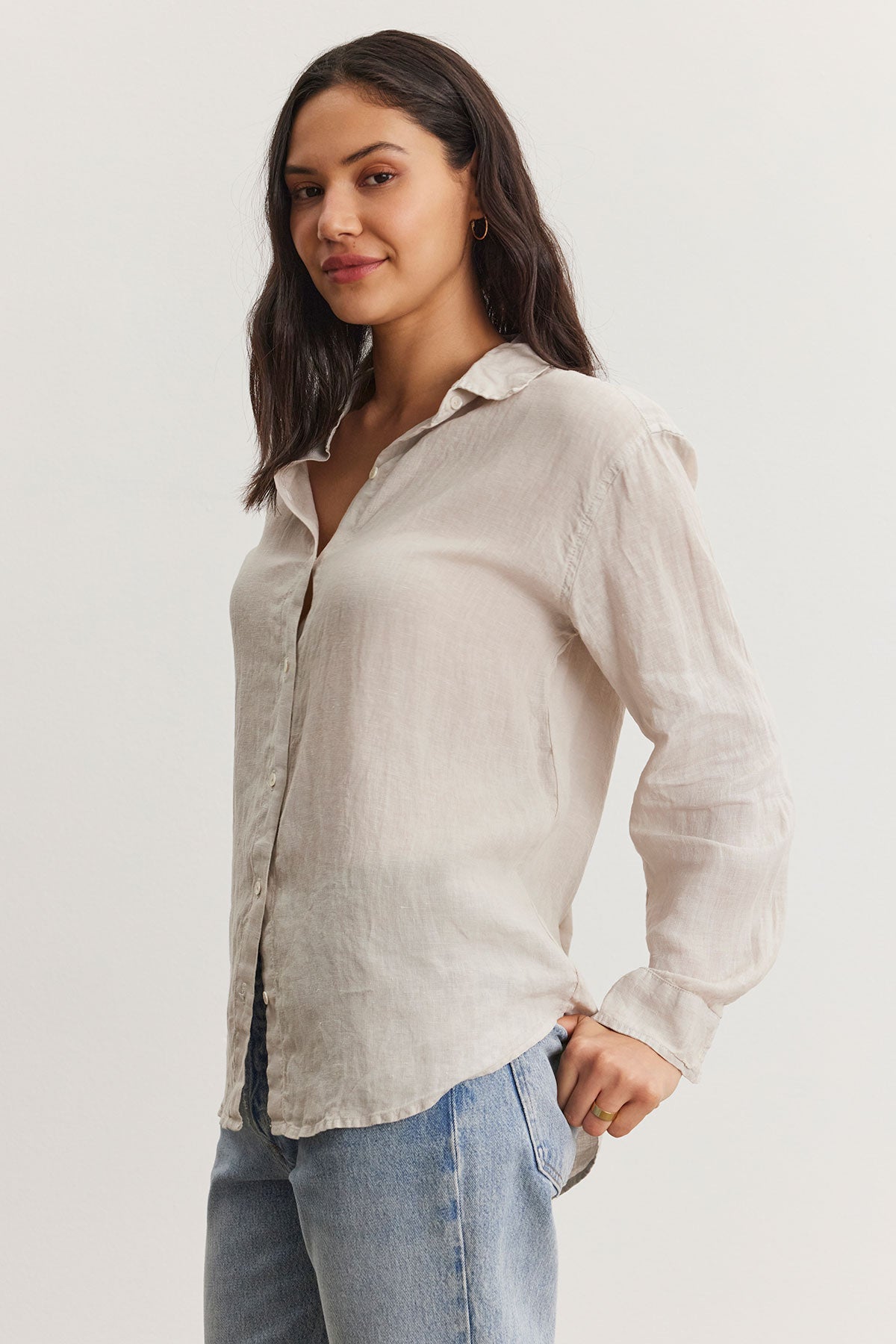 A woman wearing a Velvet by Graham & Spencer Willow Linen Button-Up Shirt and blue jeans, standing with one hand on her hip and looking relaxed.-36998739099841