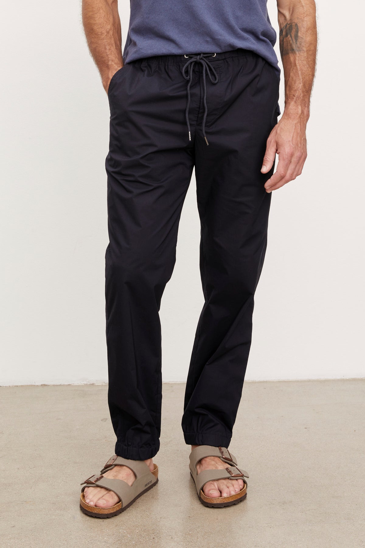   Man wearing Velvet by Graham & Spencer LAZARUS JOGGER and brown sandals, standing in a neutral pose, focusing on the lower body from waist down. 