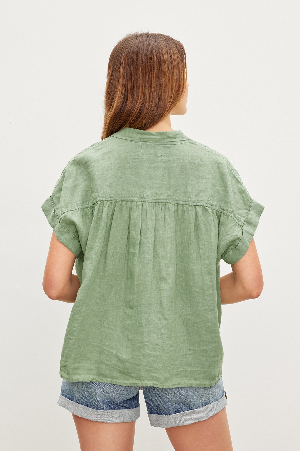 The back view of a woman wearing a Velvet by Graham & Spencer ARIA LINEN BUTTON FRONT TOP exudes comfort.-35955415089345