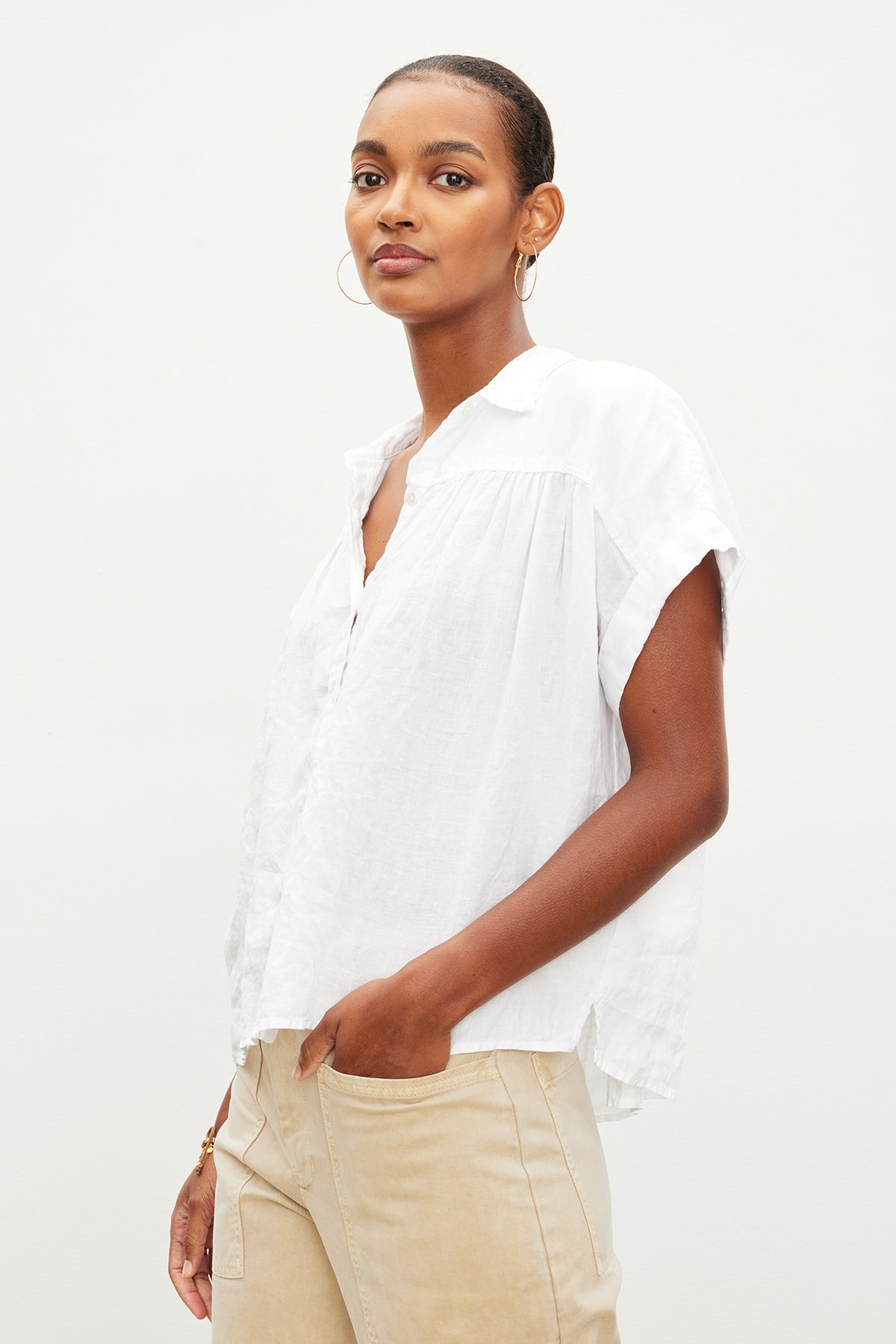 The model is wearing a white ARIA LINEN BUTTON FRONT TOP by Velvet by Graham & Spencer and tan pants, exuding comfort and timeless appeal.-35955415220417