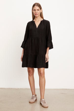 Full length front view of woman wearing Aurora Tiered Dress in black linen