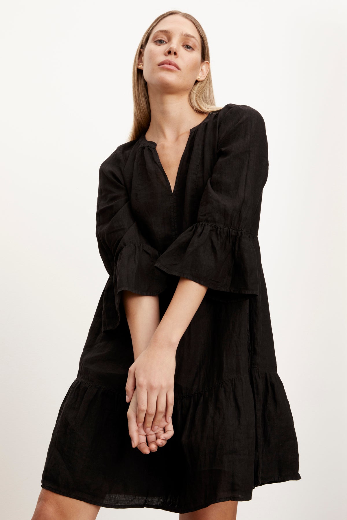   Close up of woman wearing Aurora Tiered Dress in black linen front view with model's hands clasped in front. 