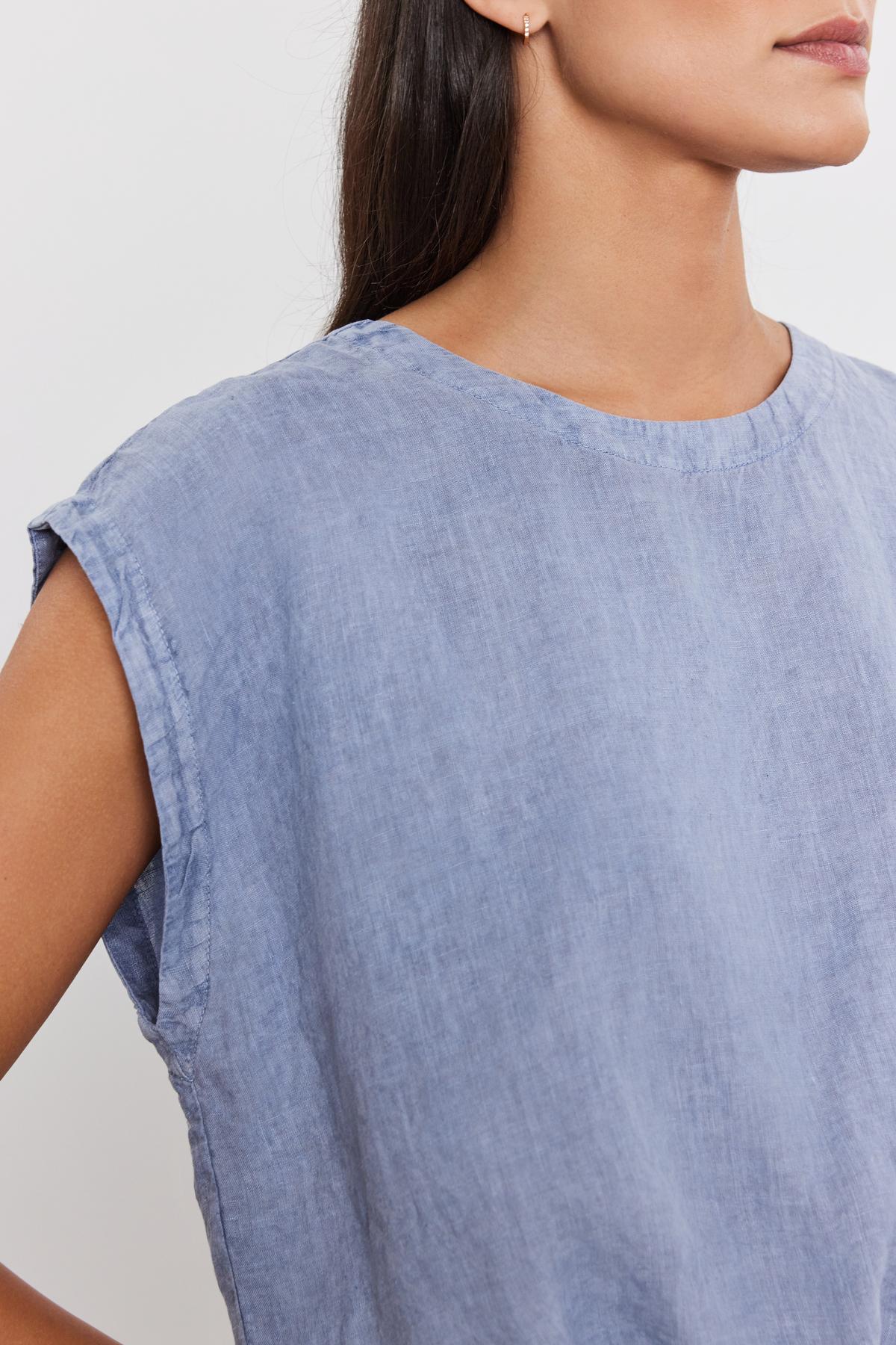   Close-up of a woman wearing a Velvet by Graham & Spencer BAYLA LINEN TOP, focusing on the shoulder design and fabric texture. 