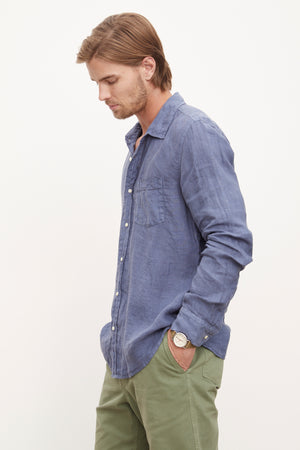 A man wearing a stylish Velvet by Graham & Spencer BENTON LINEN BUTTON-UP SHIRT and green pants.