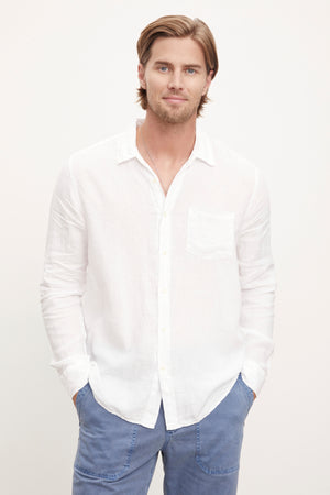 A stylish man wearing a Velvet by Graham & Spencer BENTON LINEN BUTTON-UP SHIRT and blue pants.