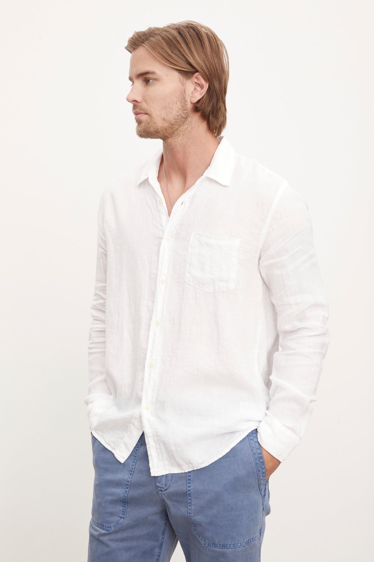 A stylish man sporting a white Velvet by Graham & Spencer Benton Linen Button-Up Shirt and blue pants.-36009360163009