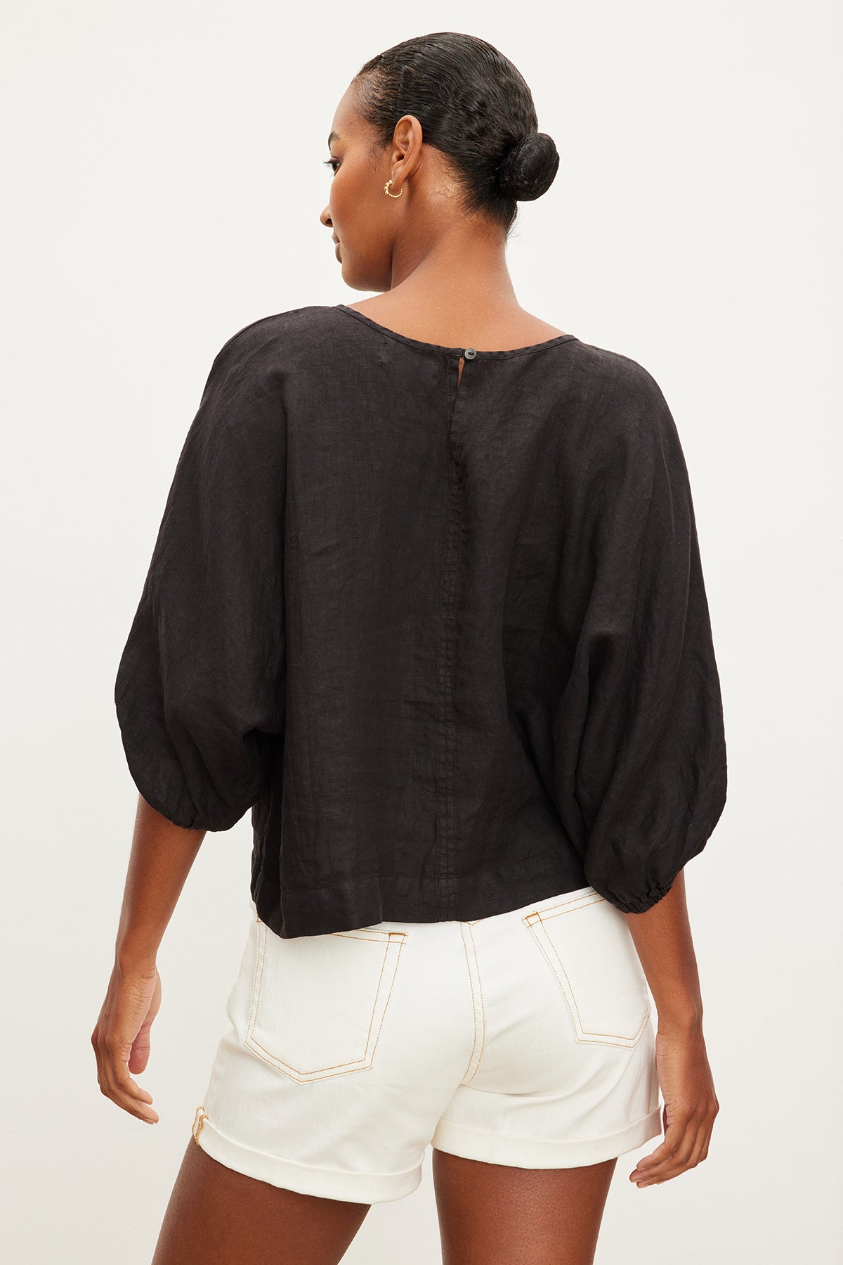 The back view of a woman wearing a Velvet by Graham & Spencer CASS LINEN CREW NECK TOP and white shorts.-35955522732225