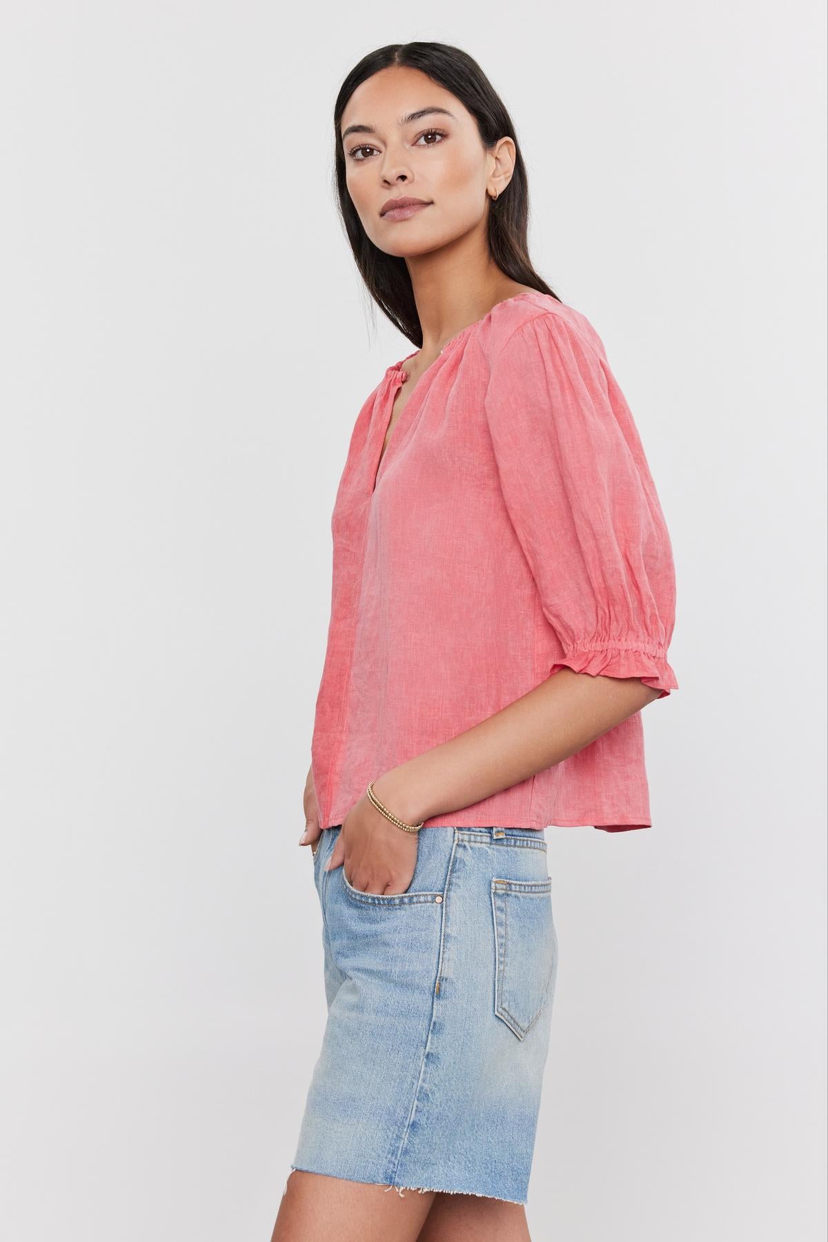   A woman in a CELINE LINEN TOP with puff sleeves and a blue denim skirt standing against a white background. Brand Name: Velvet by Graham & Spencer 