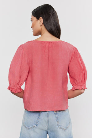 Woman pictured from behind wearing a Velvet by Graham & Spencer CELINE LINEN TOP with puff sleeves and blue jeans, standing against a white background.