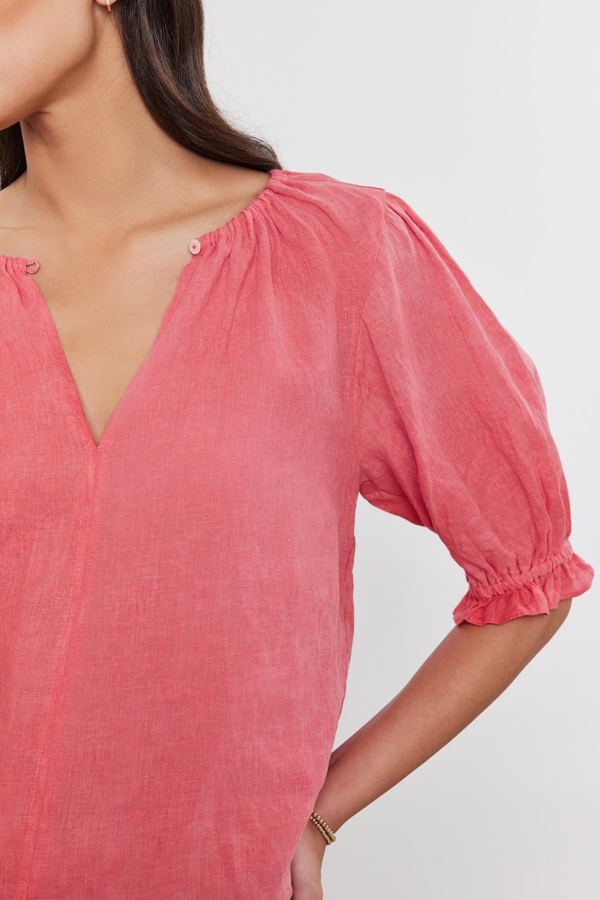   Close-up of a woman wearing a Velvet by Graham & Spencer CELINE LINEN TOP with puff sleeves and button details at the shoulder. 