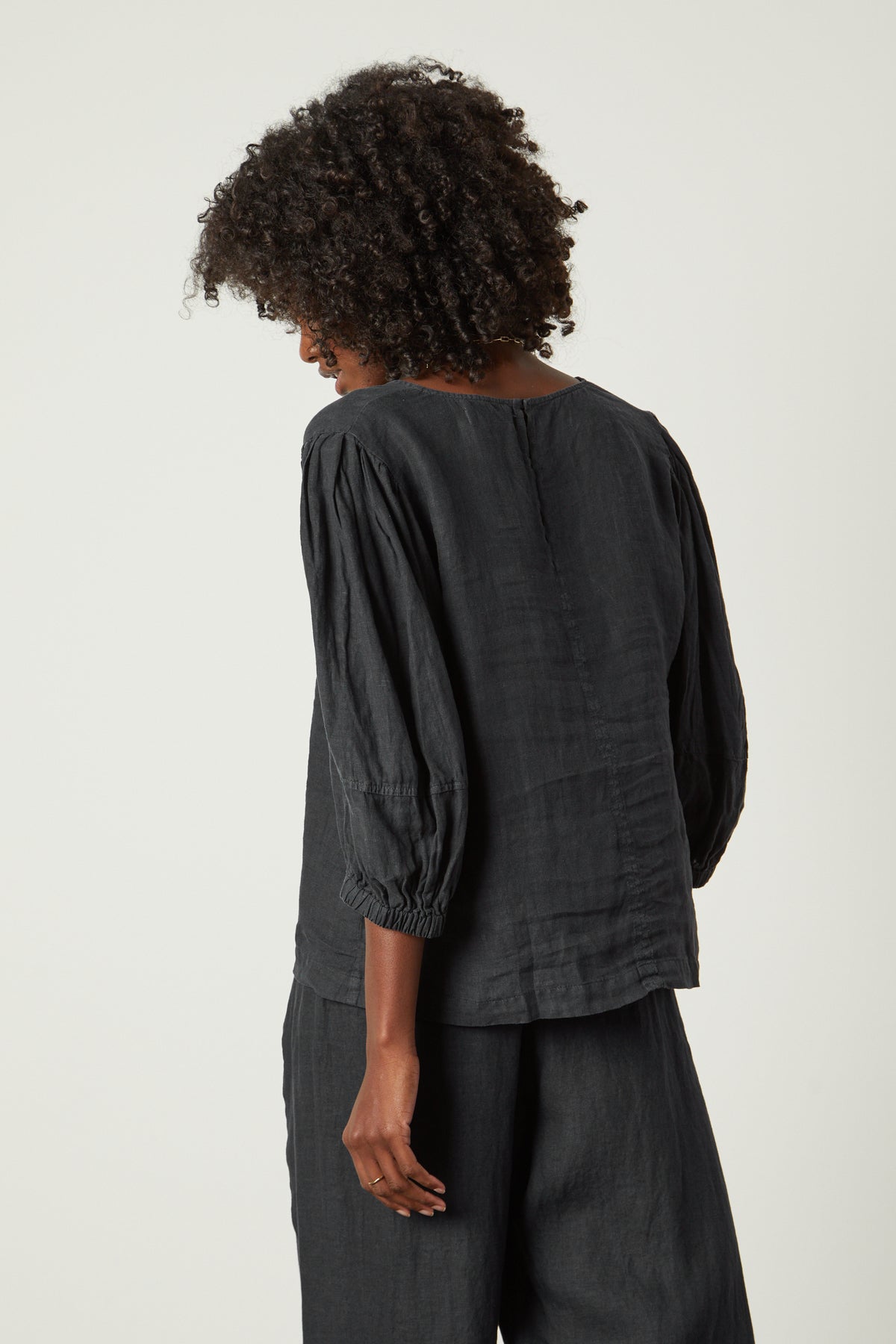 The back view of a woman wearing a Velvet by Graham & Spencer CHELSEA LINEN V-NECK TOP.-26312434811073