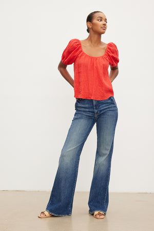 A woman wearing a Velvet by Graham & Spencer Dana Linen Scoop Neck Top and flared jeans.