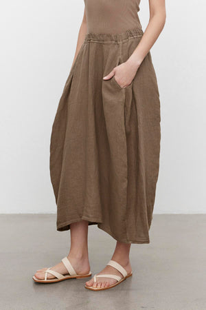 A person wearing a Velvet by Graham & Spencer FAE Linen A-Line Skirt with an elastic waistband and sandals against a plain background.