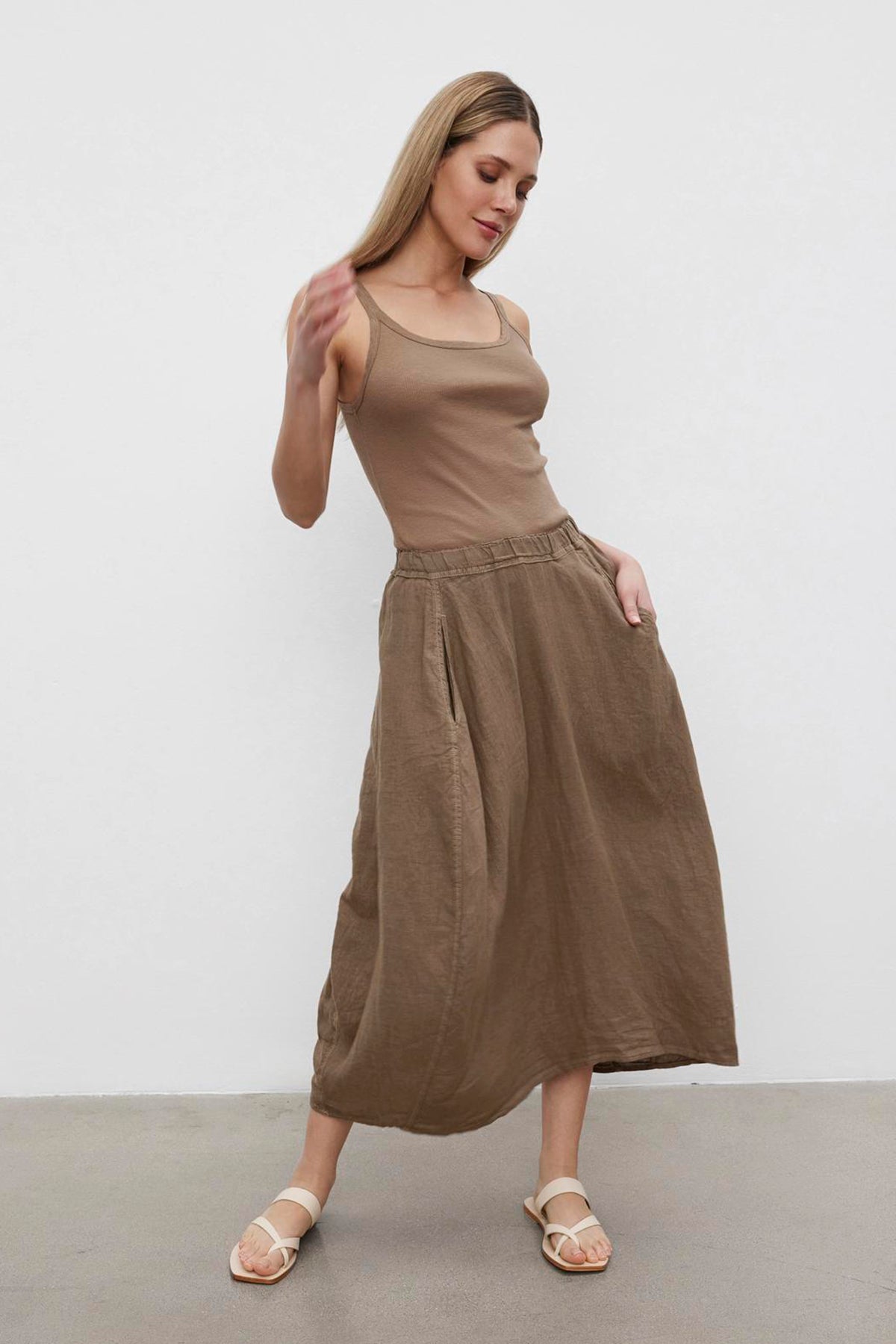   A woman in a sleeveless top and the Velvet by Graham & Spencer FAE Linen A-line skirt with an elastic waistband posing against a plain background. 
