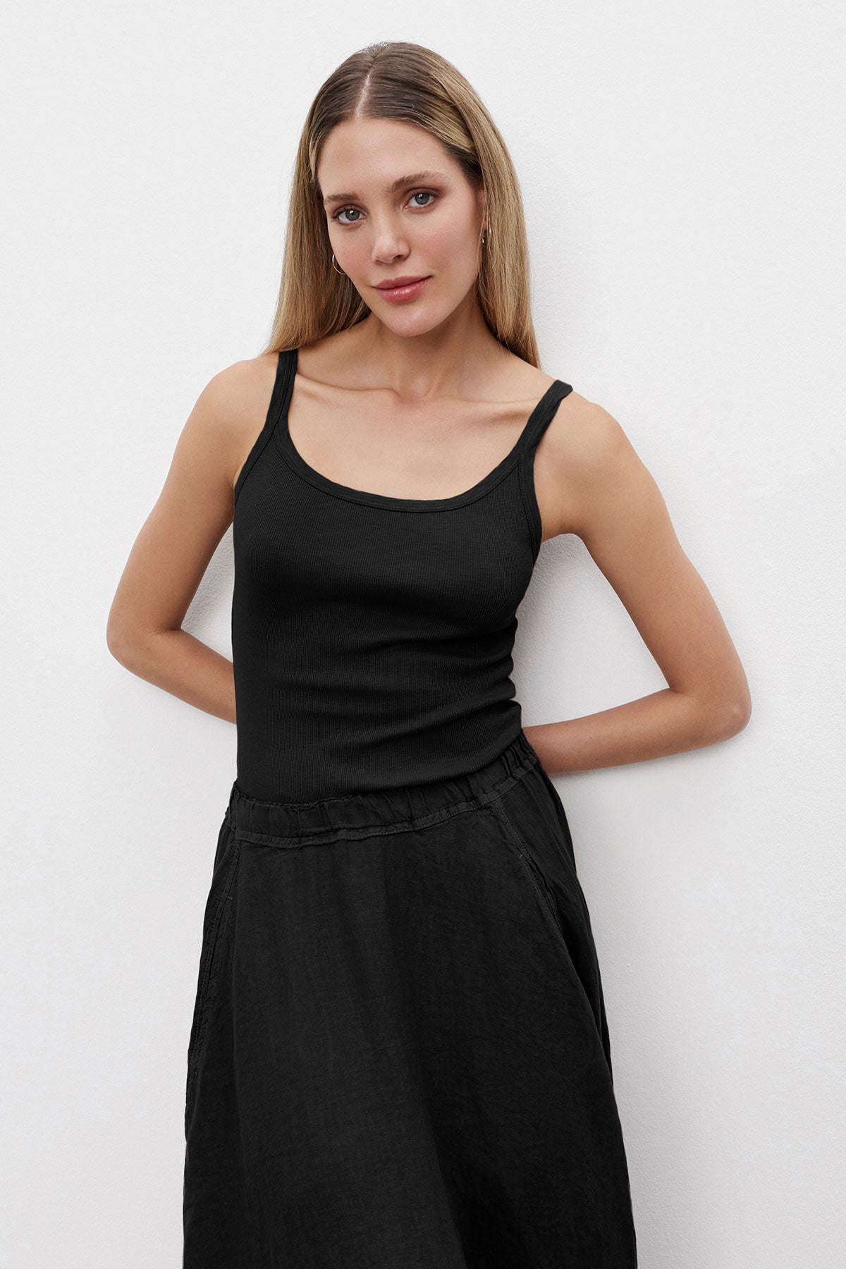   Person in a Velvet by Graham & Spencer ALIZA RIBBED COTTON LAYERING TANK with double-layer straps and black skirt standing against a white background with arms behind back. 