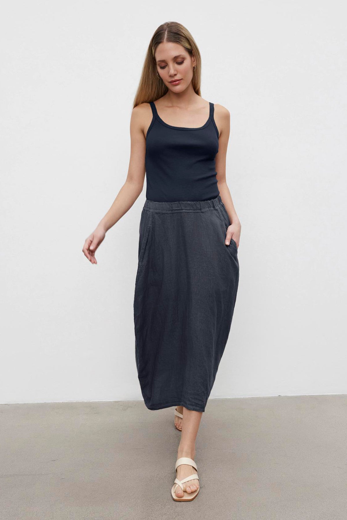 A young woman in a casual black tank top and a gray Velvet by Graham & Spencer FAE LINEN A-LINE SKIRT, standing against a plain white background.-36676258005185