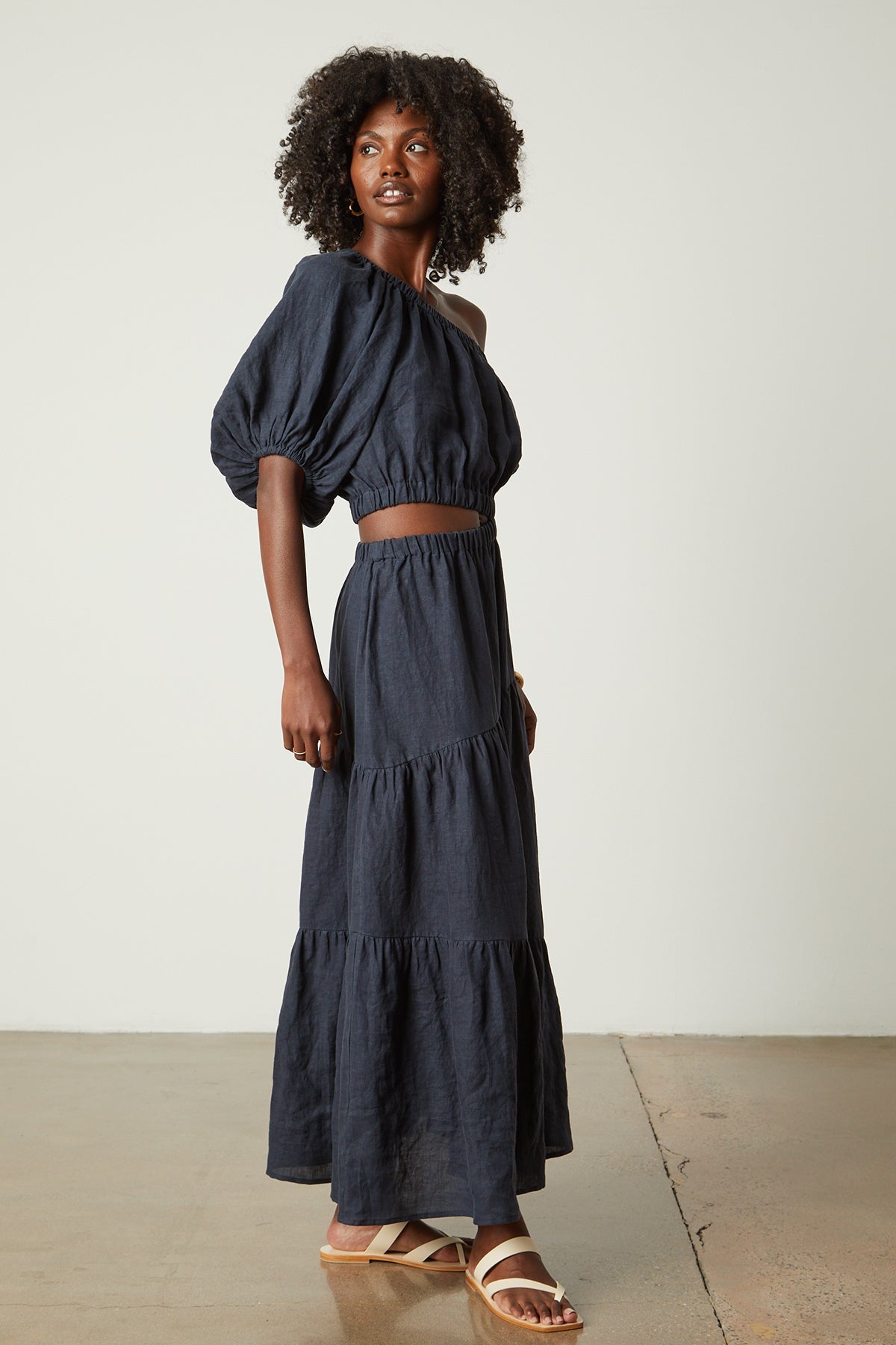 a black woman wearing the Velvet by Graham & Spencer GISELLE LINEN ONE SHOULDER DRESS with ruffled sleeves.-26496270434497