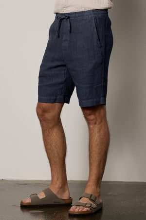 a man wearing a pair of Velvet by Graham & Spencer's JONATHAN LINEN DRAWSTRING SHORTs and sandals.