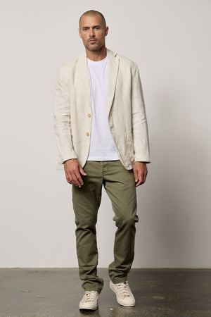A man in a tailored fit JOSHUA LINEN BLAZER by Velvet by Graham & Spencer and green pants.