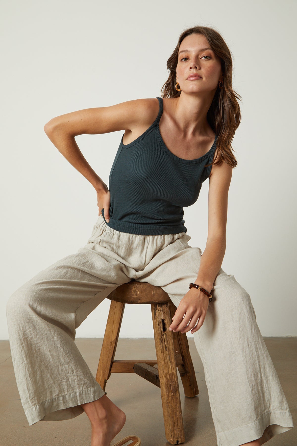   Model sitting on wooden stool wearing Aliza Layering Tank bracken with Lola pant full length front 