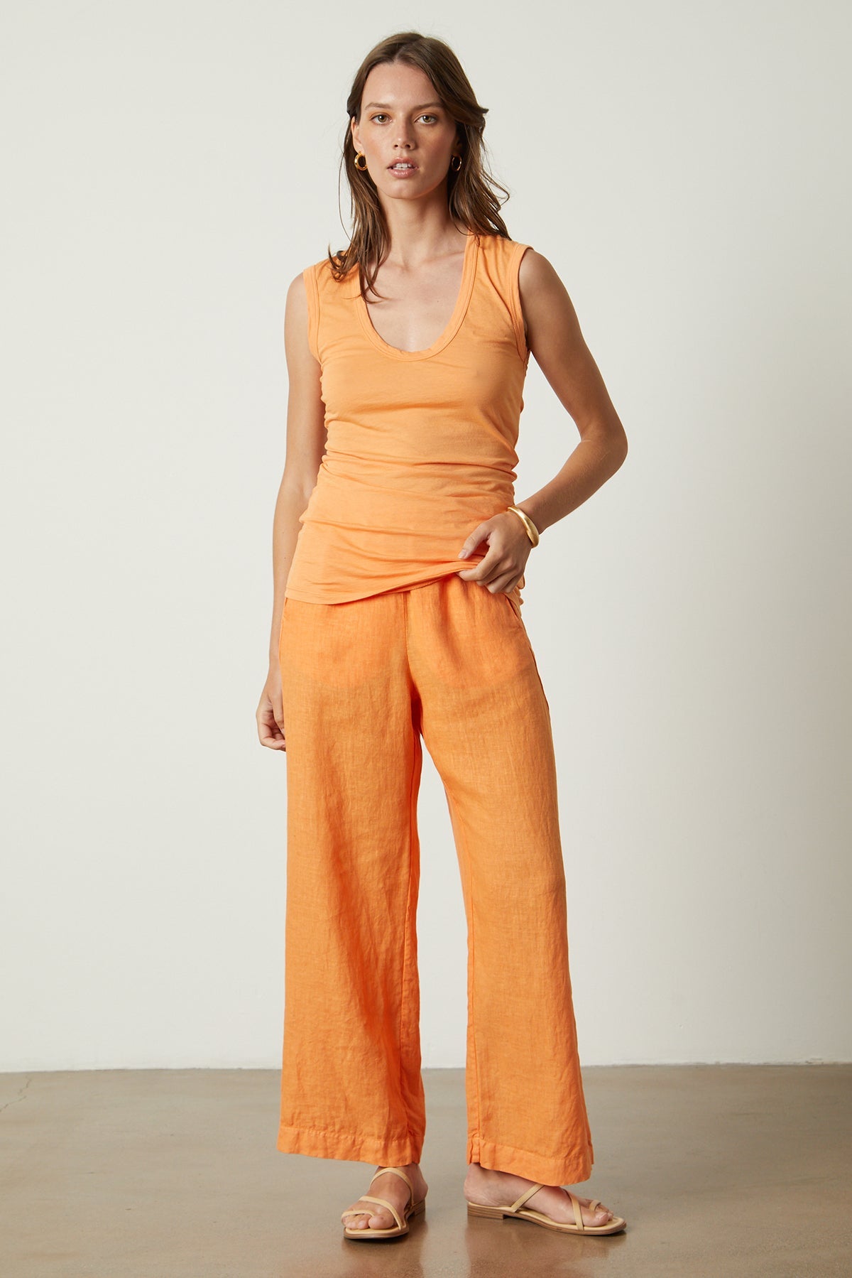   a woman wearing a Velvet by Graham & Spencer ESTINA GAUZY WHISPER FITTED TANK TOP and wide leg pants. 