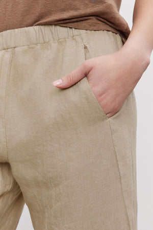 Close-up of a person's hand in the pocket of Velvet by Graham & Spencer LOLA LINEN PANT with an elastic waist.