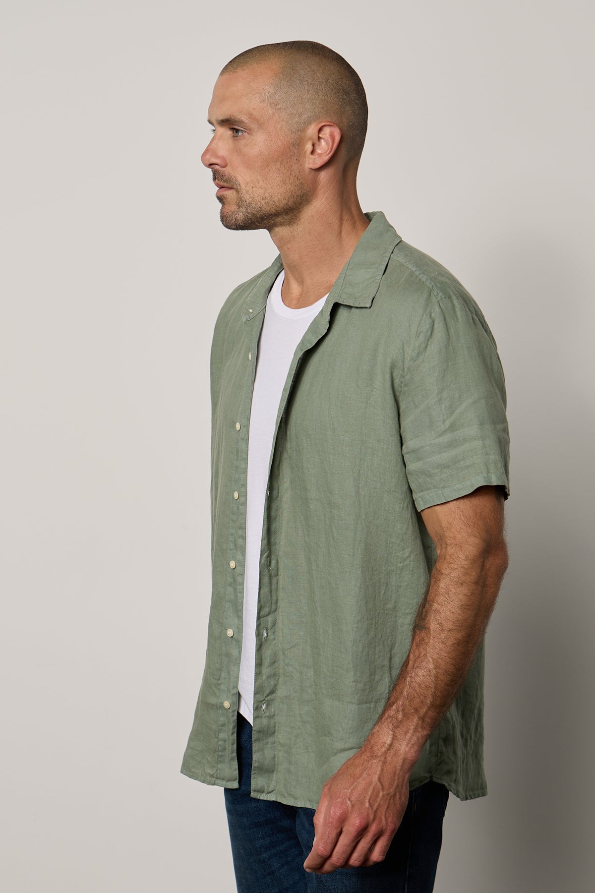   Mackie Button-Up Shirt in cactus soft green unbuttoned over white Howard Tee with dark blue denim side 