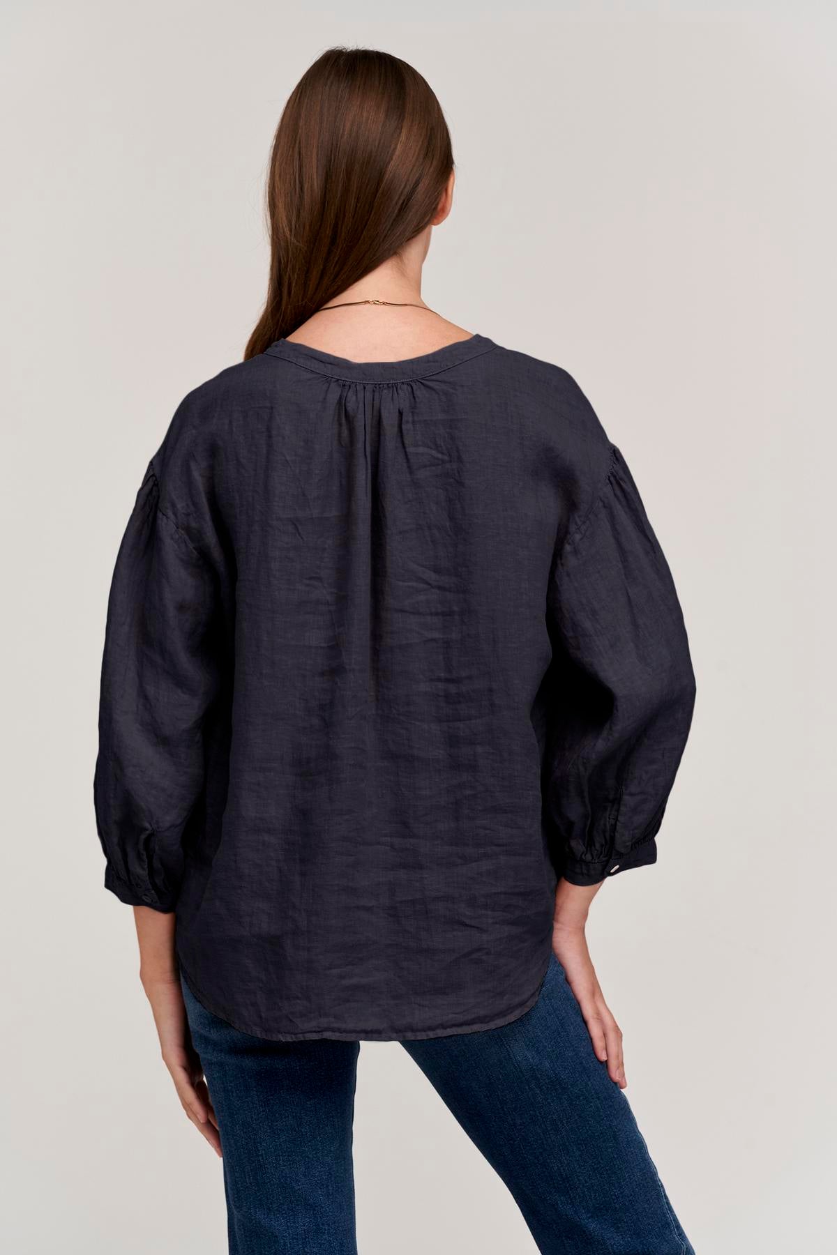   the back view of a woman wearing jeans and a MATEA LINEN BUTTON-UP BLOUSE by Velvet by Graham & Spencer. 
