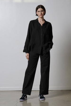 A woman is standing in a room wearing black VENTURA PANT by Velvet by Jenny Graham.