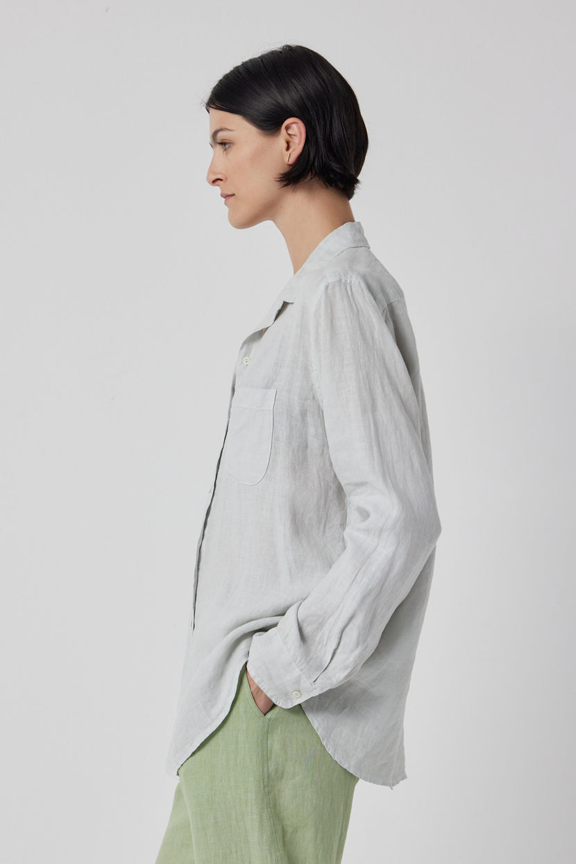 The model is wearing a grey Velvet by Jenny Graham linen button up shirt and green pants.