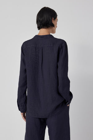 The back view of a woman wearing a MULHOLLAND SHIRT by Velvet by Jenny Graham and pants with a relaxed silhouette.