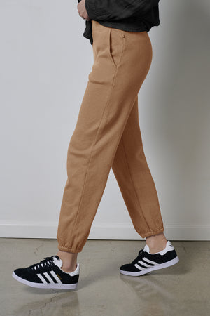 A woman wearing ZUMA SWEATPANT joggers and Velvet by Jenny Graham black sneakers.