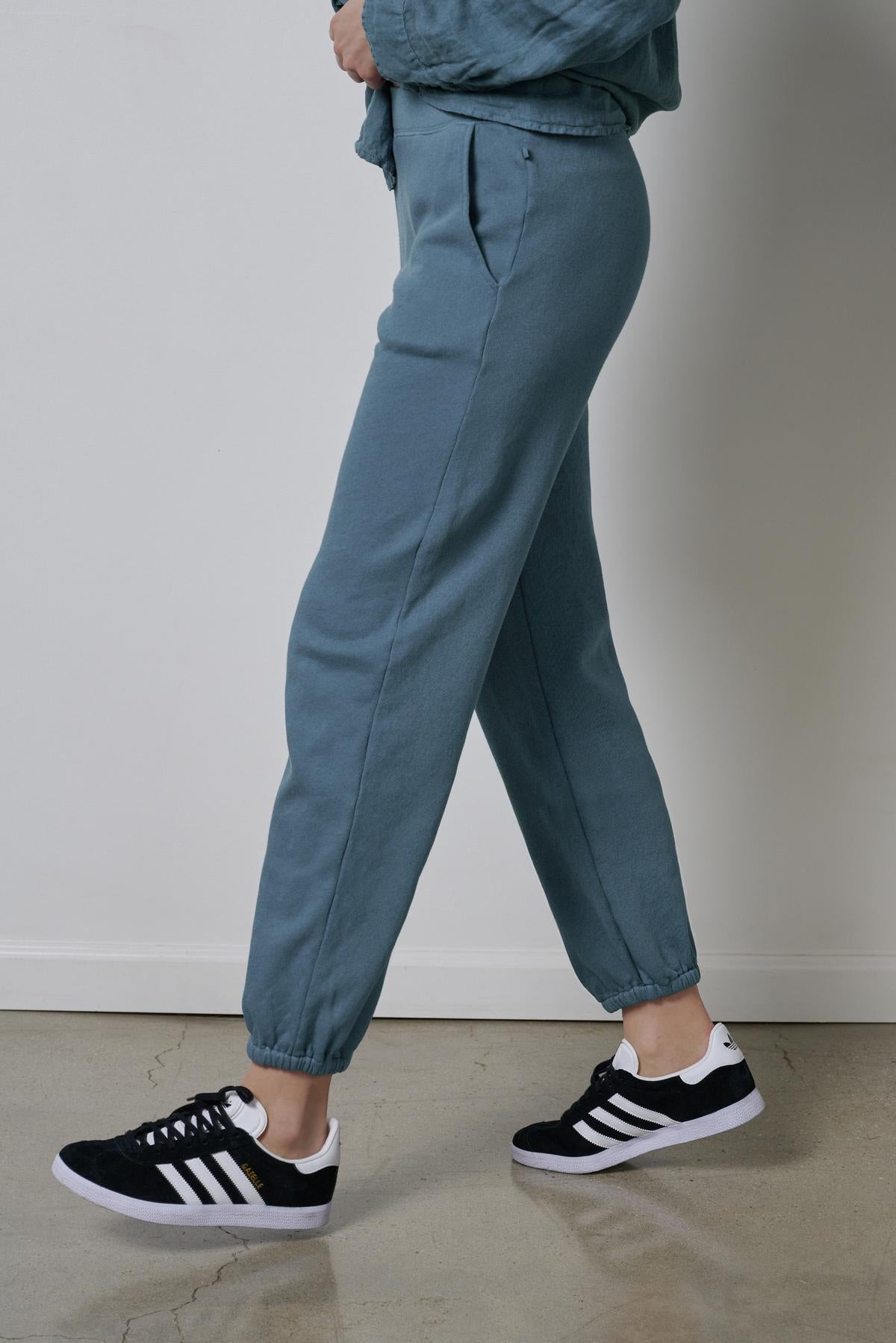   Person standing sideways showcasing sustainable fashion with Velvet by Jenny Graham Zuma Sweatpants and black sneakers. 