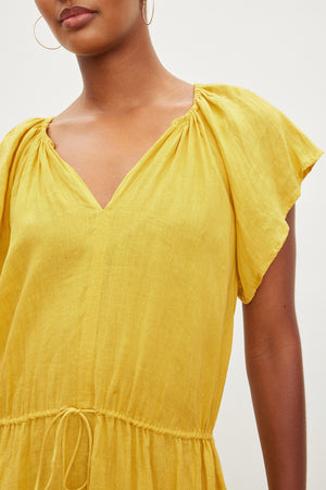 Close-up of a woman wearing a Velvet by Graham & Spencer PEPPER LINEN V-NECK DRESS with gathered sleeves and a drawstring waist, focusing on the neckline and shoulder details.