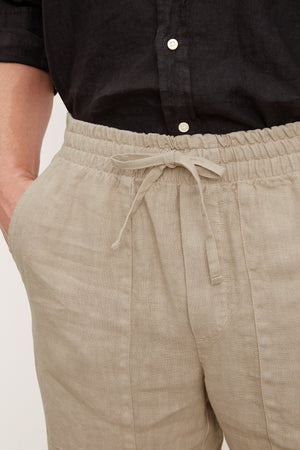 Close-up of a person wearing Velvet by Graham & Spencer's Phelan Linen Pant and a black shirt, focusing on the waist and hip area.
