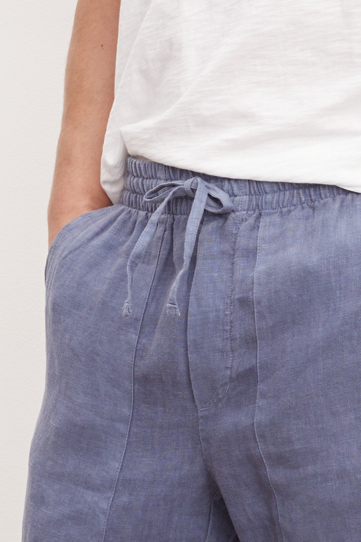  Close-up of a person wearing Velvet by Graham & Spencer's Phelan Linen Pant and a white t-shirt, focusing on the waist area. 