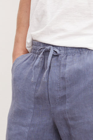 Close-up of a person wearing Velvet by Graham & Spencer's Phelan Linen Pant and a white t-shirt, focusing on the waist area.