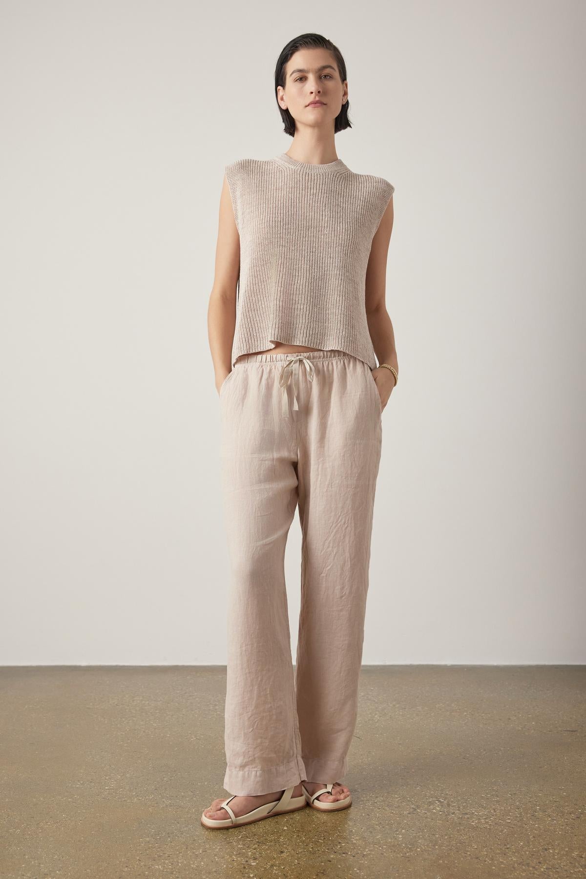 Woman standing in a neutral setting, wearing a sleeveless beige top, Velvet by Jenny Graham PICO LINEN PANTS, and sandals, with a slight smile and hands at sides.-36863287492801