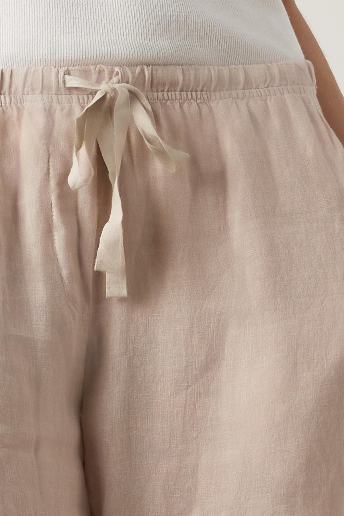 Close-up of a person wearing Velvet by Jenny Graham's PICO LINEN PANT in light pink with an elastic waist, focusing on the waist area.-36863287591105