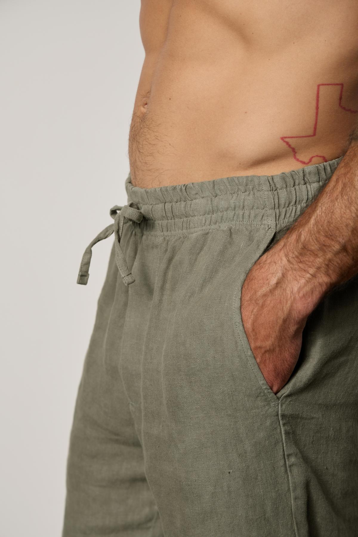   A man wearing Velvet by Graham & Spencer khaki shorts with a tattoo on his chest. 